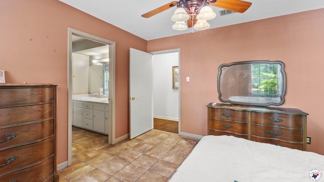 bedroom featuring visible vents, a sink, light tile patterned flooring, baseboards, and ensuite bathroom