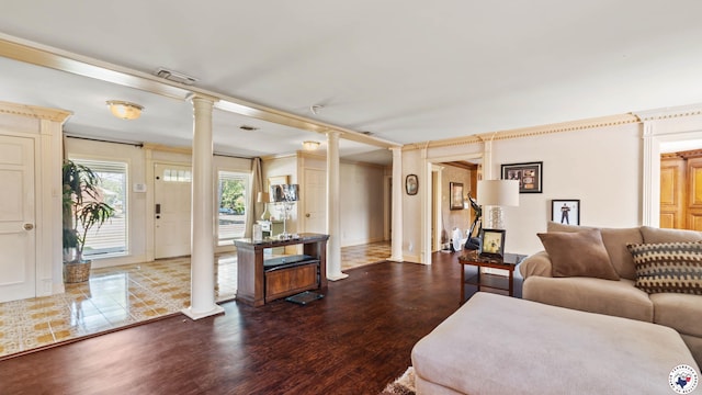living area featuring visible vents, baseboards, ornate columns, wood finished floors, and crown molding