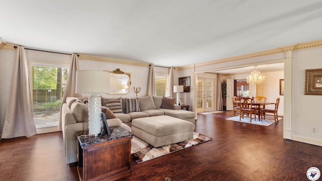 living area with baseboards, wood finished floors, a notable chandelier, and crown molding