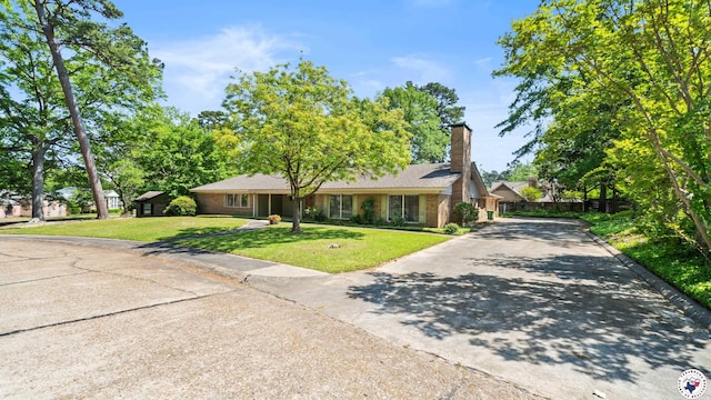 ranch-style home with a front lawn, driveway, and a chimney