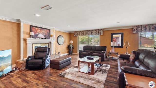 living room featuring wood finished floors, visible vents, ornamental molding, baseboards, and a glass covered fireplace