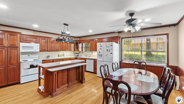 kitchen featuring light countertops, white appliances, light wood-style floors, a kitchen island, and crown molding