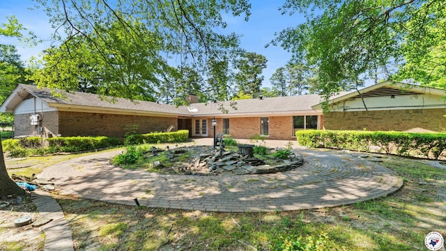 back of property with a chimney and brick siding
