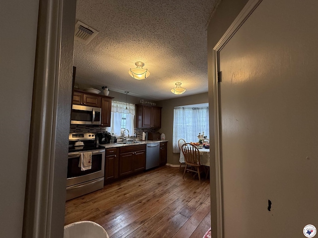 567 Mc 257, Texarkana, AR 71854 - kitchen with appliances with stainless steel finishes, a textured ceiling, light countertops, dark wood-style floors, and decorative backsplash