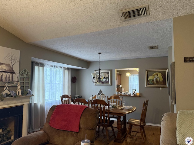 567 Mc 257, Texarkana, AR 71854 - dining area featuring a textured ceiling, hardwood / wood-style floors, a chandelier, and a fireplace