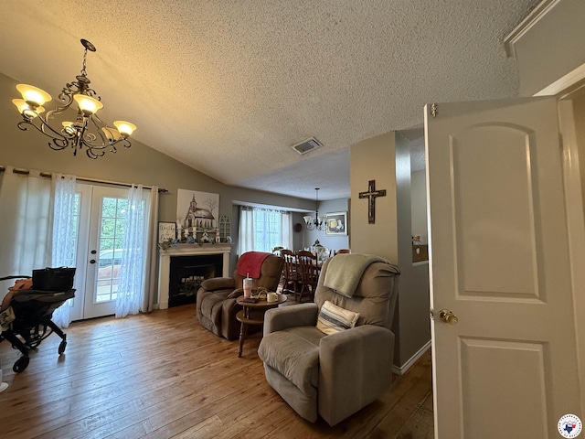 567 Mc 257, Texarkana, AR 71854 - living area featuring a chandelier, a textured ceiling, light wood-style floors, vaulted ceiling, and a fireplace