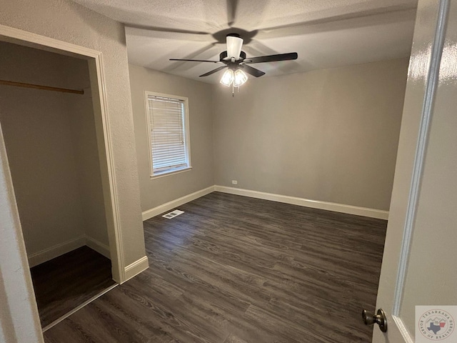 unfurnished bedroom featuring ceiling fan, dark wood-type flooring, and a textured ceiling