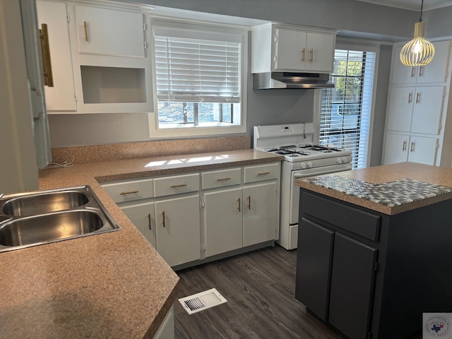 kitchen with white cabinets, gas range gas stove, a kitchen island, decorative light fixtures, and sink