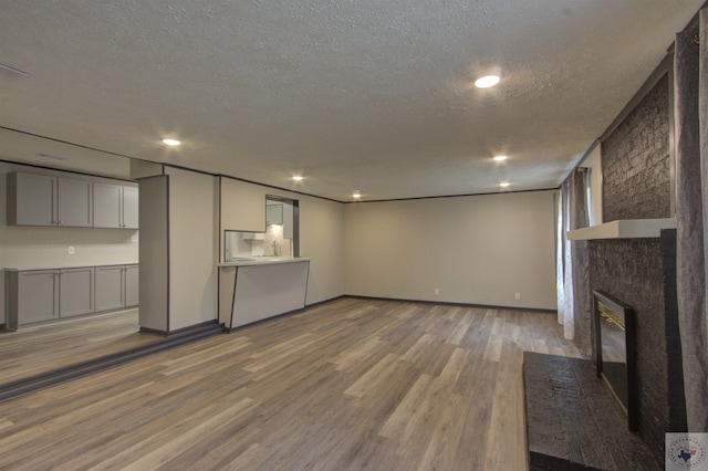 unfurnished living room featuring hardwood / wood-style flooring, a textured ceiling, and a fireplace