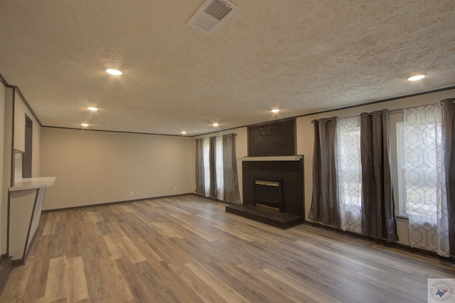 unfurnished living room featuring a fireplace, a healthy amount of sunlight, a textured ceiling, and hardwood / wood-style flooring