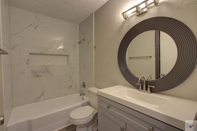 full bathroom with a textured ceiling, toilet, vanity, and tiled shower / bath