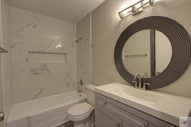 full bathroom with a textured ceiling, toilet, vanity, and tiled shower / bath