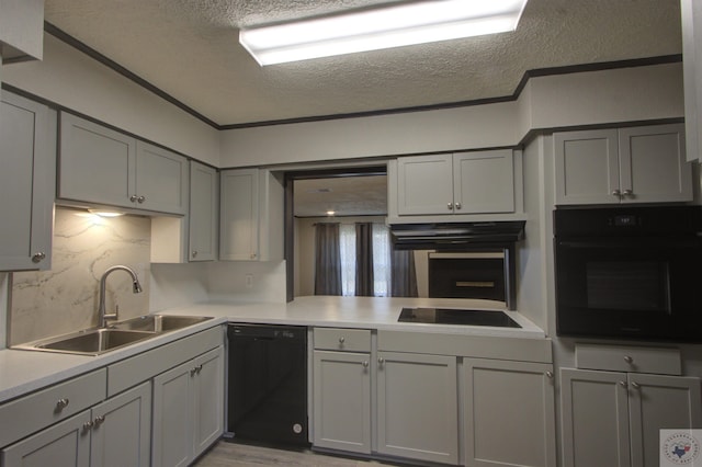 kitchen featuring black appliances, a textured ceiling, gray cabinetry, sink, and backsplash