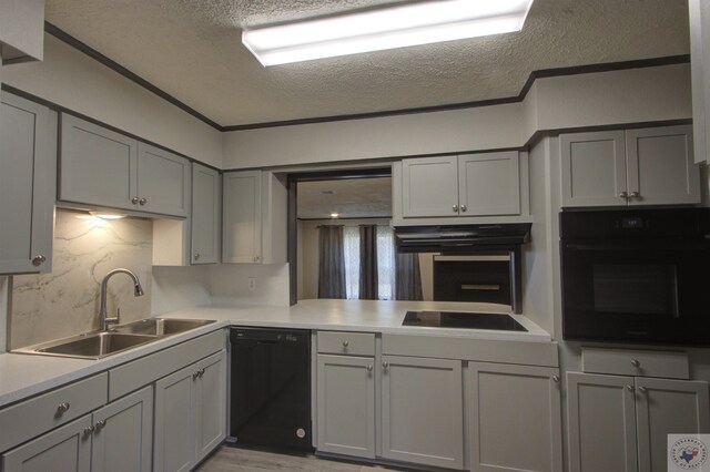 kitchen featuring black appliances, a textured ceiling, gray cabinetry, sink, and backsplash