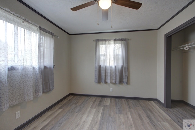 unfurnished bedroom with a textured ceiling, light hardwood / wood-style floors, a closet, ceiling fan, and crown molding