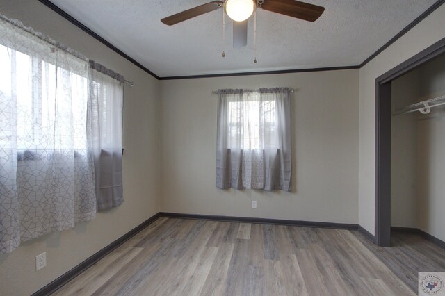 unfurnished bedroom with a textured ceiling, light hardwood / wood-style floors, a closet, ceiling fan, and crown molding