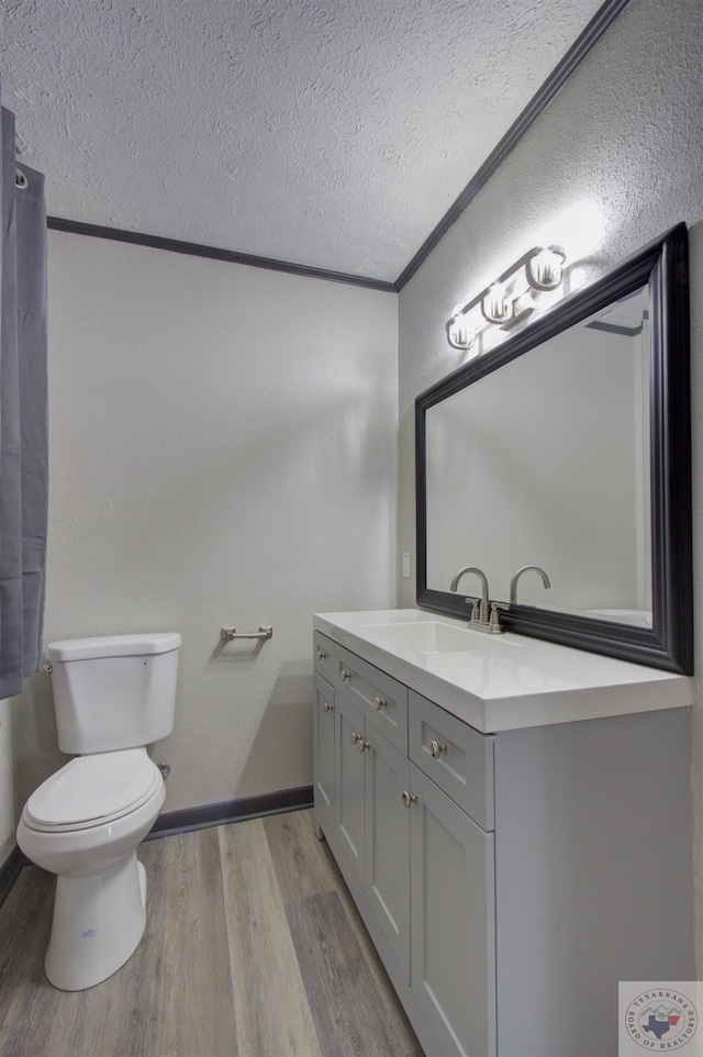 bathroom with toilet, hardwood / wood-style floors, crown molding, a textured ceiling, and vanity