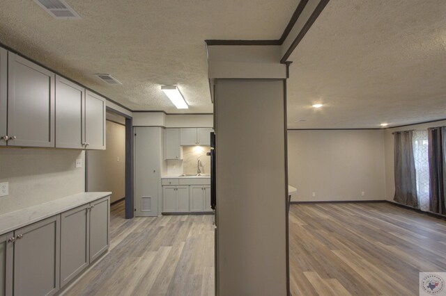 kitchen featuring sink, light hardwood / wood-style flooring, a textured ceiling, and gray cabinets