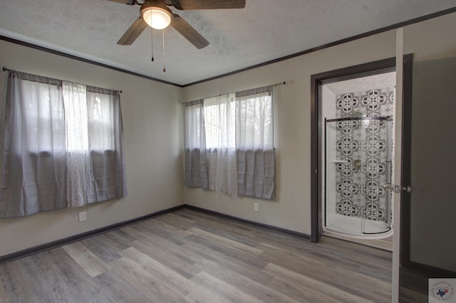 empty room with light wood-type flooring, ceiling fan, and a textured ceiling