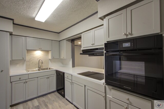 kitchen featuring a textured ceiling, black appliances, sink, backsplash, and light wood-type flooring