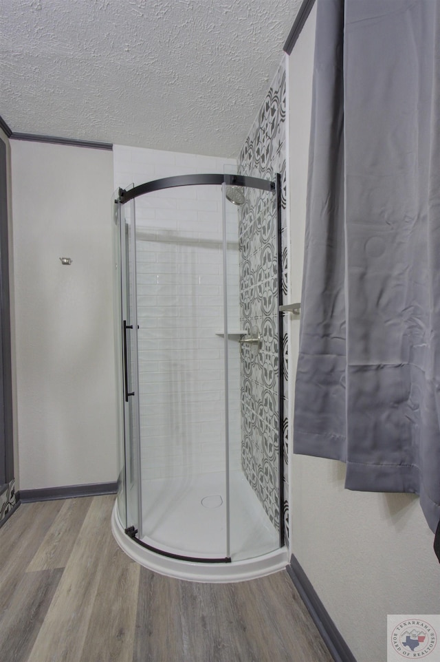 bathroom with a shower with door, a textured ceiling, and wood-type flooring