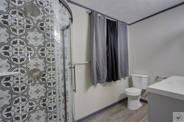 bathroom with hardwood / wood-style floors, a textured ceiling, toilet, walk in shower, and vanity