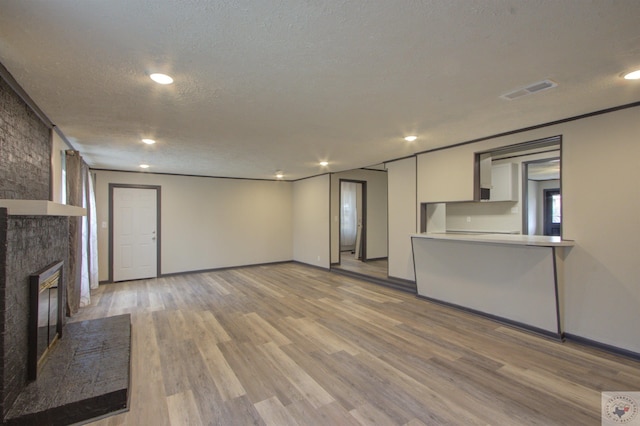 unfurnished living room featuring light hardwood / wood-style flooring, a fireplace, and a textured ceiling