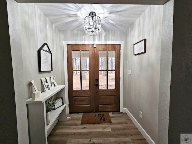 entryway featuring french doors, dark wood-type flooring, and a notable chandelier