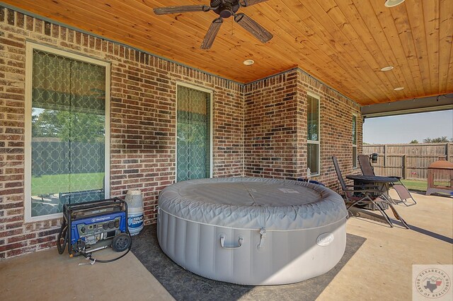 view of patio / terrace featuring a jacuzzi, fence, and ceiling fan