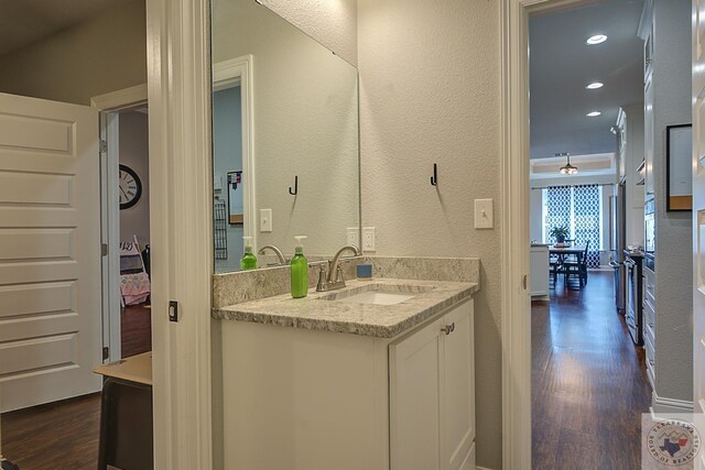 bathroom featuring recessed lighting, wood finished floors, vanity, and a textured wall