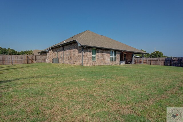 rear view of property with brick siding, central AC unit, a lawn, and a fenced backyard