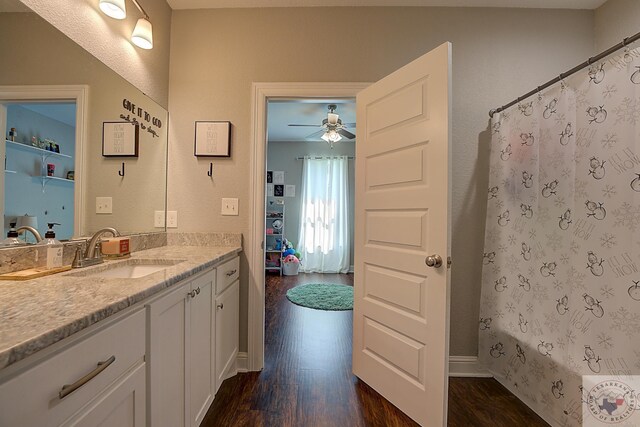 bathroom featuring shower / tub combo with curtain, a ceiling fan, wood finished floors, baseboards, and vanity