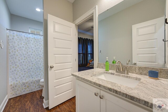 full bath featuring a shower with shower curtain, toilet, wood finished floors, and vanity