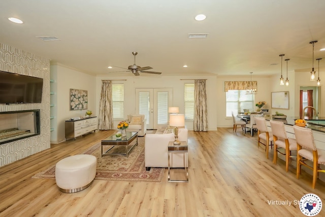 10 King Ranch Rd, Texarkana, TX 75503 - living room featuring light wood-style flooring, a large fireplace, ceiling fan, crown molding, and a chandelier