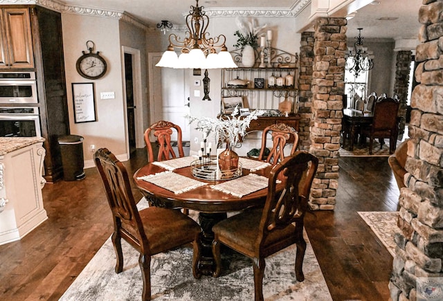 dining room featuring crown molding, decorative columns, dark wood-type flooring, and an inviting chandelier