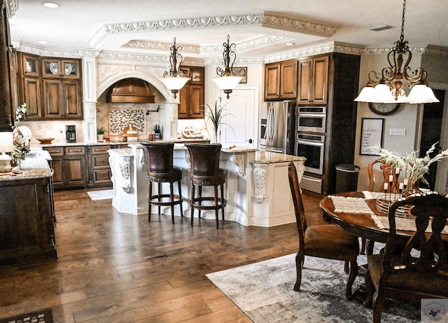 kitchen featuring decorative light fixtures, a kitchen island with sink, appliances with stainless steel finishes, and tasteful backsplash