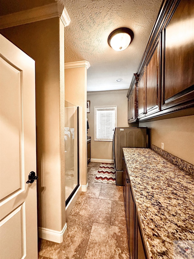 washroom featuring independent washer and dryer, a textured ceiling, and ornamental molding