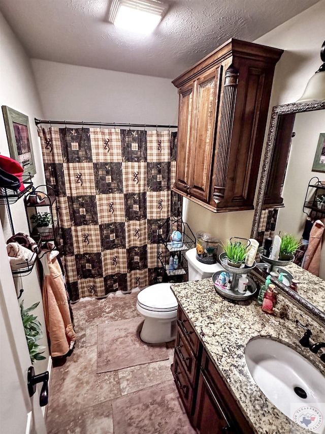 bathroom featuring curtained shower, a textured ceiling, toilet, and vanity