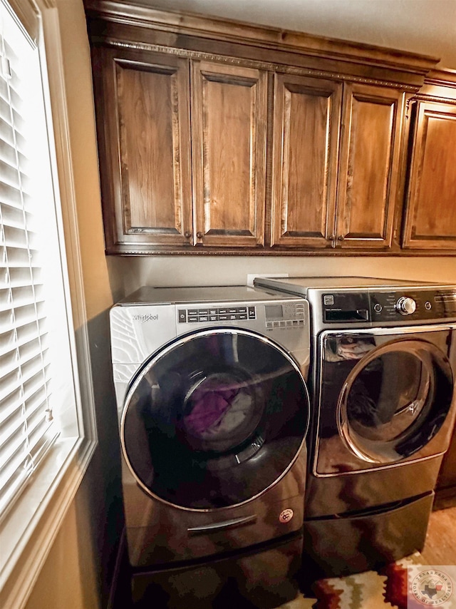 washroom with a healthy amount of sunlight, cabinets, and independent washer and dryer