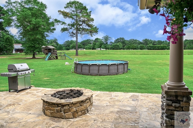 view of patio / terrace with an outdoor fire pit, a playground, and a grill