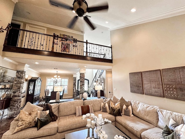 living room featuring ornamental molding, ceiling fan with notable chandelier, and ornate columns