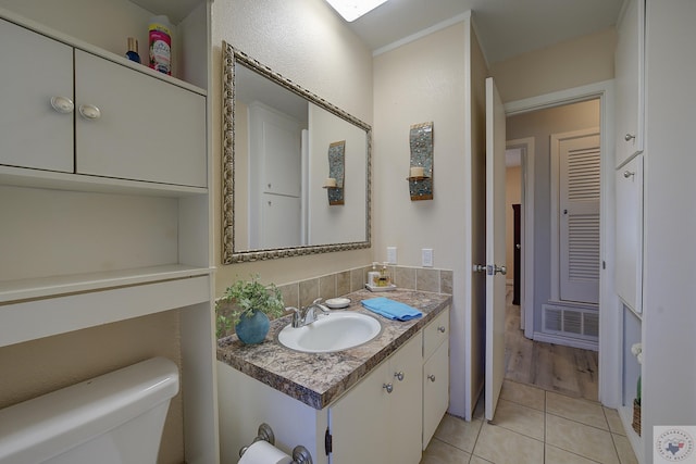 half bath with tile patterned floors, toilet, and vanity