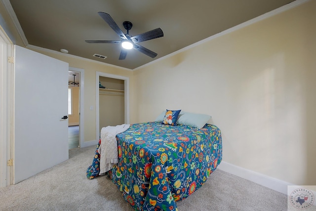 carpeted bedroom featuring a ceiling fan, baseboards, ornamental molding, and a closet