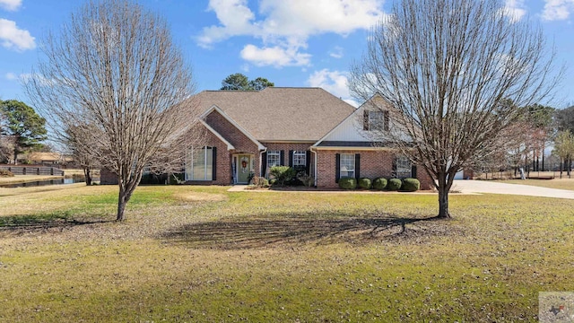 view of front of property featuring brick siding, roof with shingles, and a front yard