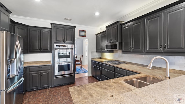 kitchen with crown molding, backsplash, appliances with stainless steel finishes, a sink, and dark cabinets