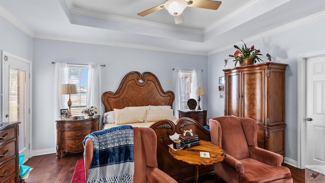 bedroom featuring baseboards, dark wood-style floors, ceiling fan, a tray ceiling, and crown molding