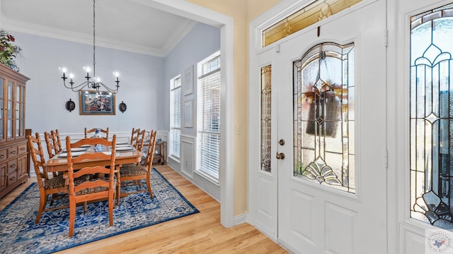 entryway featuring light wood-type flooring, an inviting chandelier, ornamental molding, and a wealth of natural light