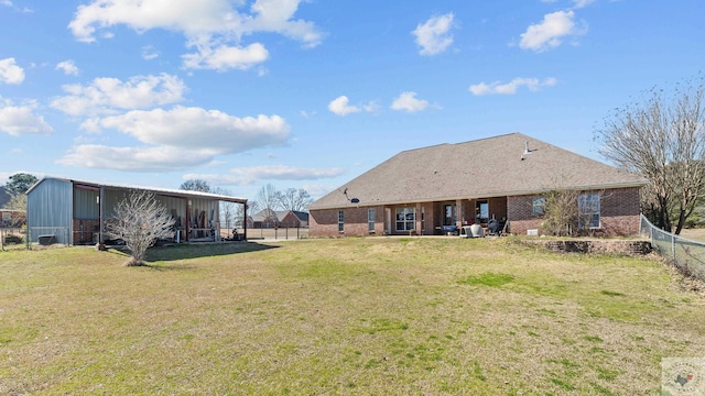 back of house with a pole building, fence, a lawn, and brick siding