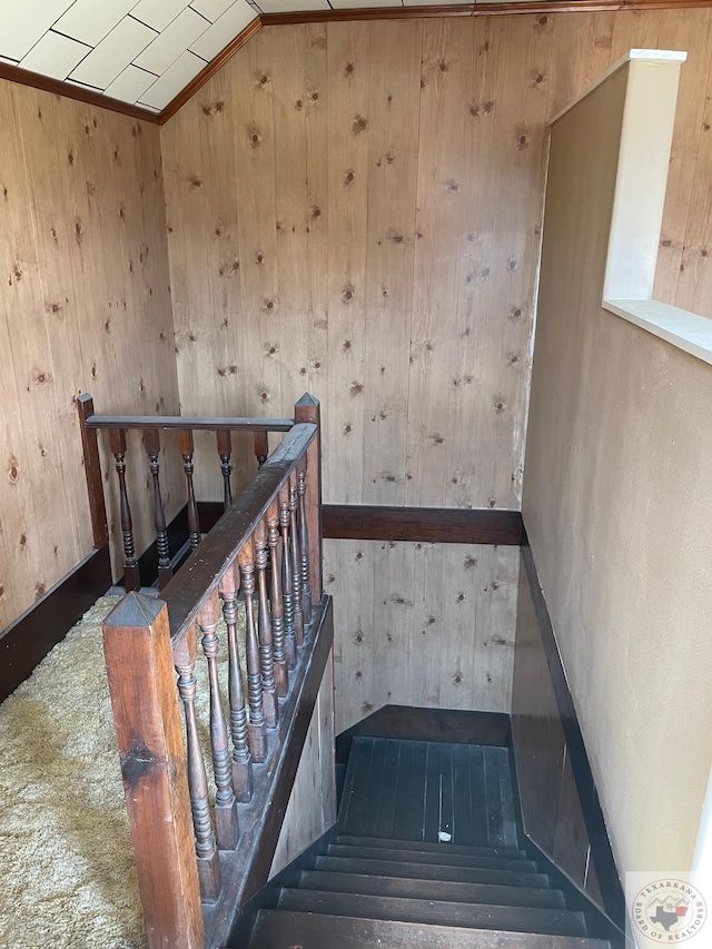 staircase featuring wood walls and vaulted ceiling