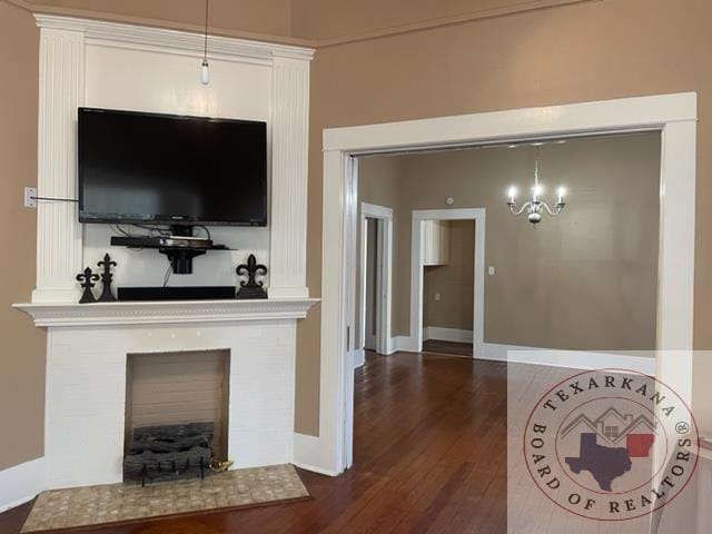 living room featuring dark hardwood / wood-style floors, a tile fireplace, and an inviting chandelier